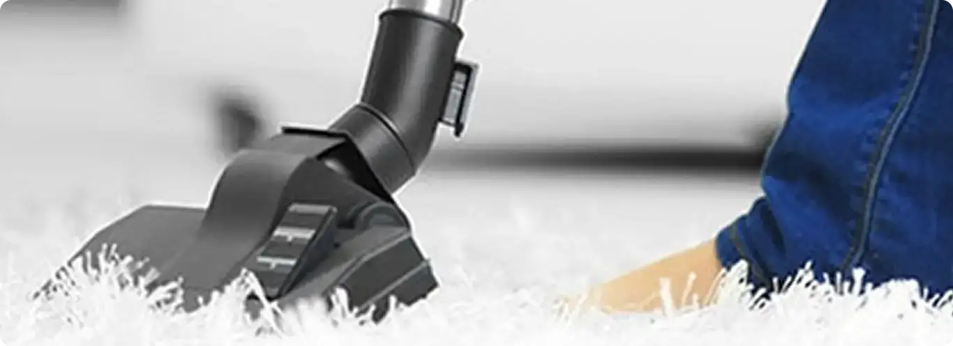 Close-up of a professional vacuuming a white carpet in Chelsea.